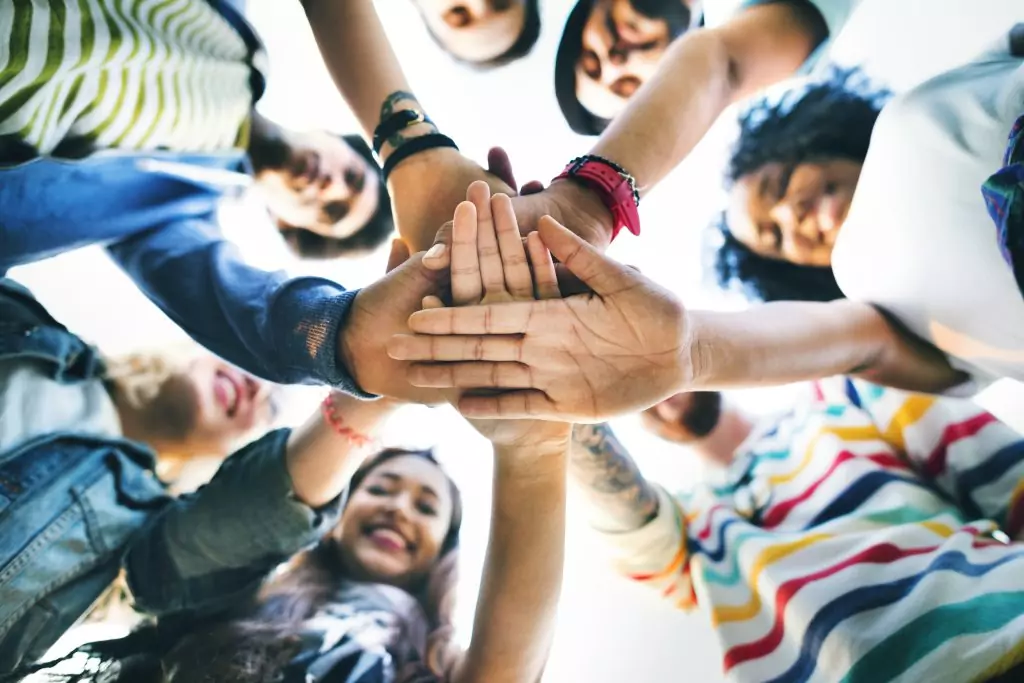 Un groupe de jeunes qui se tape dans les mains en formant une ronde