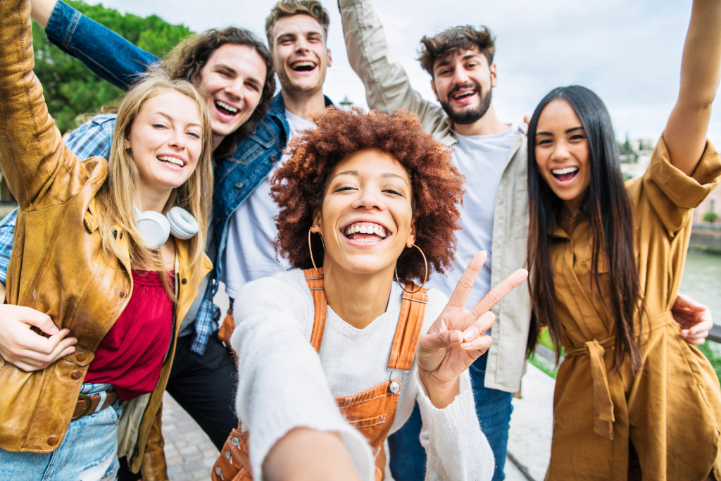 Photo d'un groupe de jeunes qui sont contents les bras en l'air en mode selfie
